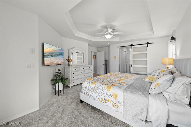 carpeted bedroom featuring a barn door, ceiling fan, and a tray ceiling