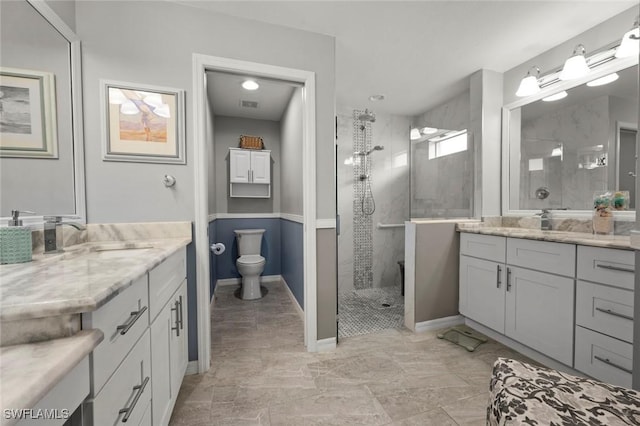 bathroom with a tile shower, vanity, and toilet