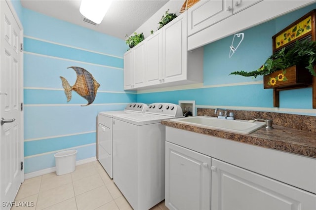 laundry area featuring sink, light tile patterned floors, cabinets, and washing machine and clothes dryer