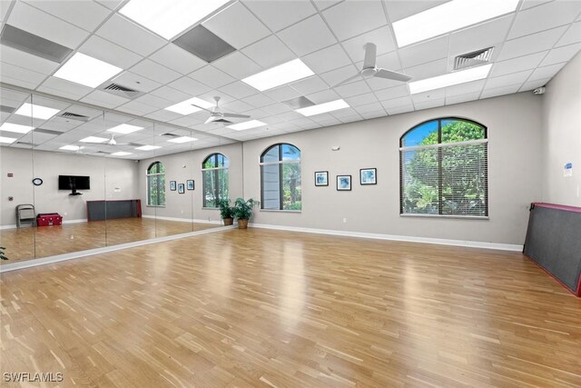 exercise area with ceiling fan, a paneled ceiling, and light hardwood / wood-style flooring