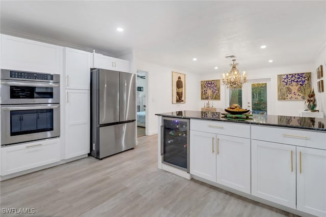 kitchen featuring appliances with stainless steel finishes, beverage cooler, light wood-type flooring, and white cabinets