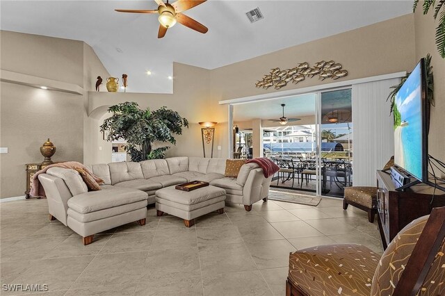 living room featuring ceiling fan, light tile patterned floors, and vaulted ceiling