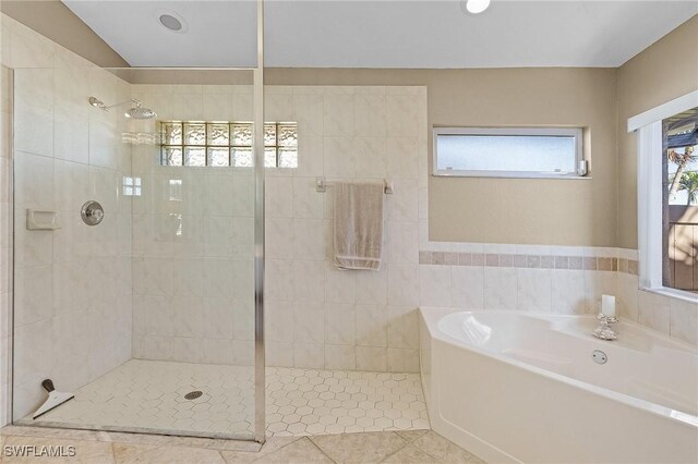 bathroom with tile walls, independent shower and bath, and tile patterned floors