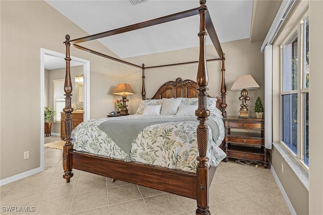 tiled bedroom featuring vaulted ceiling and connected bathroom