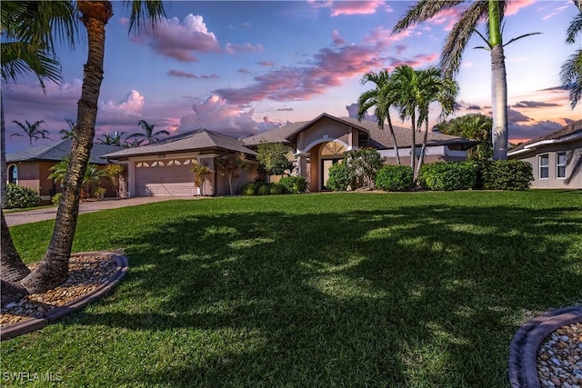 view of front of property featuring a lawn, stucco siding, driveway, and a garage
