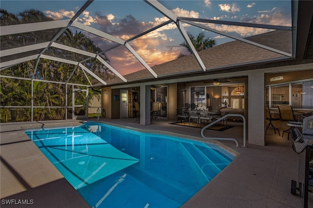 pool at dusk featuring a patio and a lanai