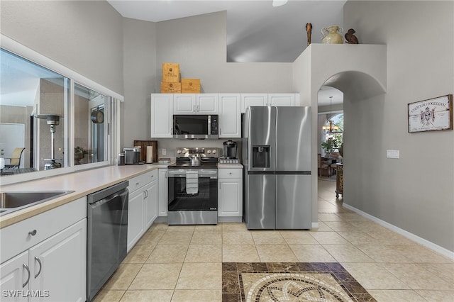 kitchen featuring high vaulted ceiling, light tile patterned floors, stainless steel appliances, and white cabinetry