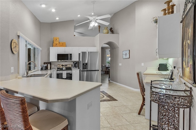 kitchen with appliances with stainless steel finishes, high vaulted ceiling, sink, white cabinetry, and kitchen peninsula