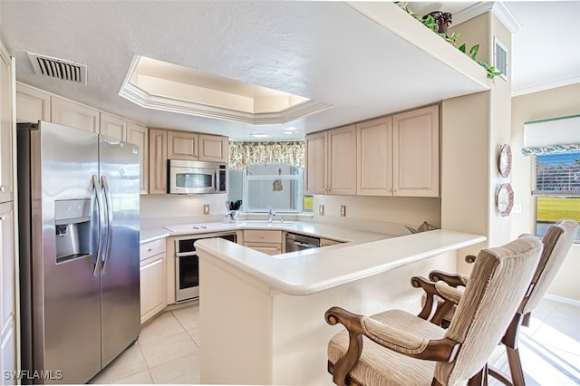 kitchen with appliances with stainless steel finishes, kitchen peninsula, sink, and a raised ceiling