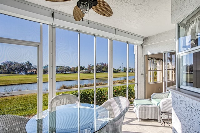 sunroom featuring a water view and ceiling fan