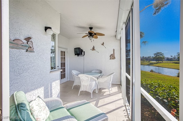 sunroom / solarium featuring a water view and ceiling fan