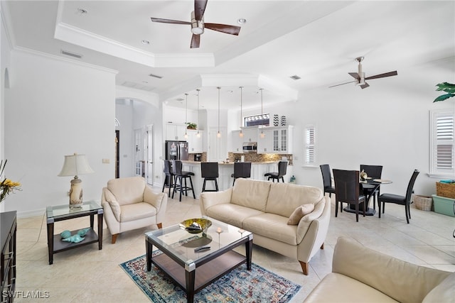 living room with ornamental molding, light tile patterned flooring, ceiling fan, and a tray ceiling