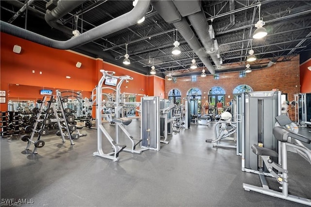 workout area with a high ceiling and brick wall