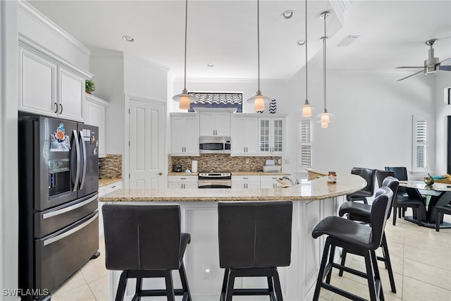 kitchen featuring white cabinetry, appliances with stainless steel finishes, a kitchen island with sink, and hanging light fixtures