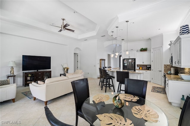 dining room with a tray ceiling, ornamental molding, ceiling fan, and light tile patterned flooring