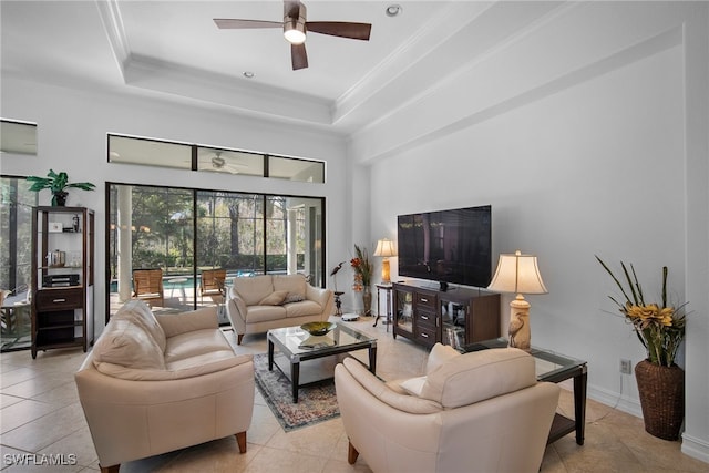 living room featuring a raised ceiling, ornamental molding, light tile patterned floors, and ceiling fan