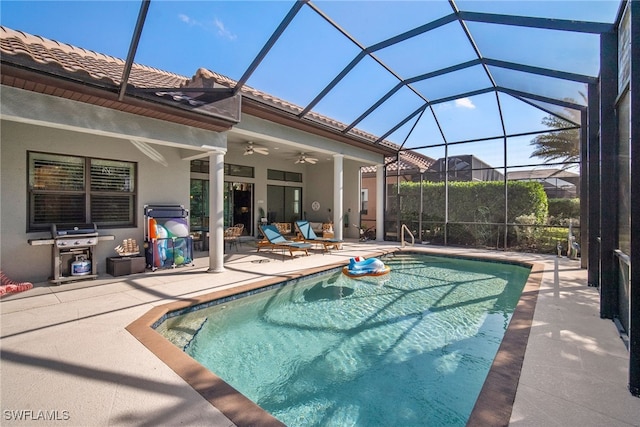 view of pool with grilling area, ceiling fan, glass enclosure, and a patio area