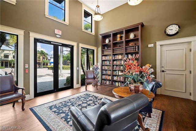 living area with hardwood / wood-style flooring, french doors, and a high ceiling