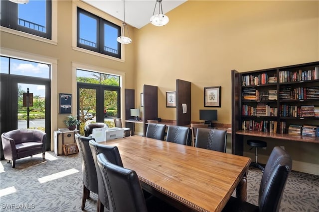 carpeted dining space with a high ceiling and french doors