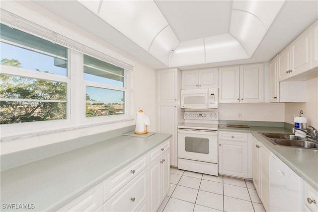 kitchen with white cabinetry, sink, light tile patterned flooring, and white appliances