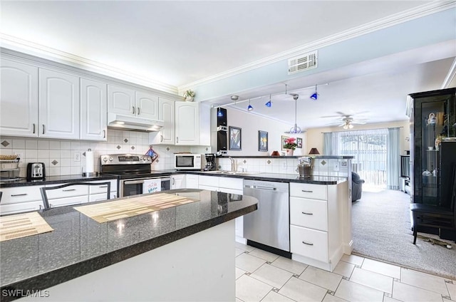 kitchen featuring white cabinetry, stainless steel appliances, crown molding, and dark stone counters