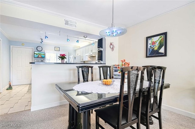 carpeted dining area featuring crown molding and track lighting