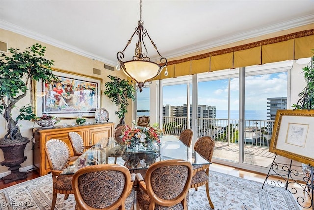 dining area featuring hardwood / wood-style flooring, ornamental molding, and a water view