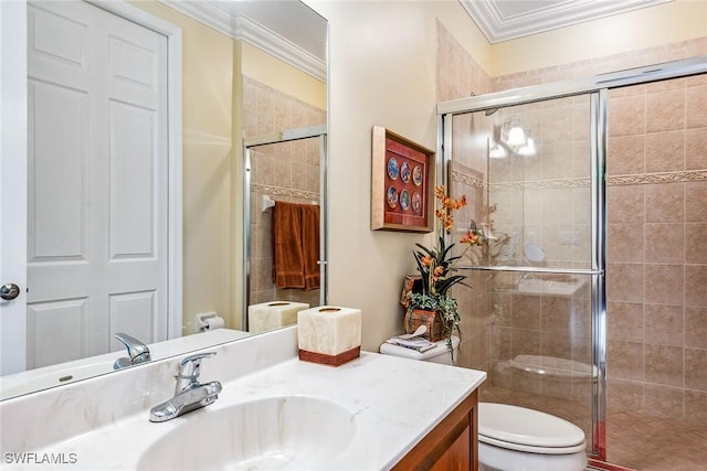 bathroom featuring ornamental molding, toilet, vanity, and a shower with shower door