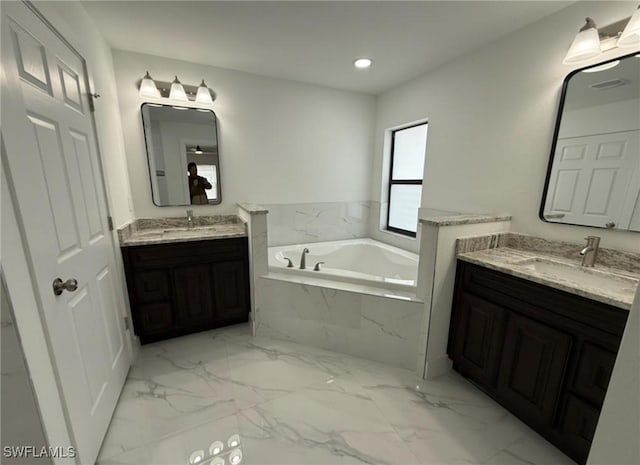 bathroom with vanity and tiled bath