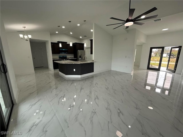 kitchen with ceiling fan with notable chandelier, stainless steel appliances, light stone counters, decorative light fixtures, and vaulted ceiling