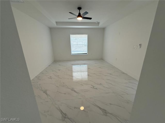 spare room with ceiling fan and a tray ceiling