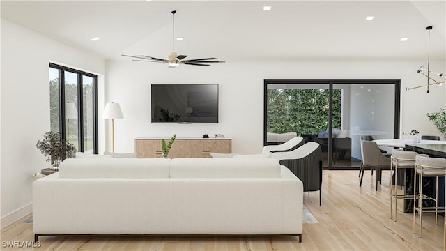 living room featuring ceiling fan, lofted ceiling, and light hardwood / wood-style floors