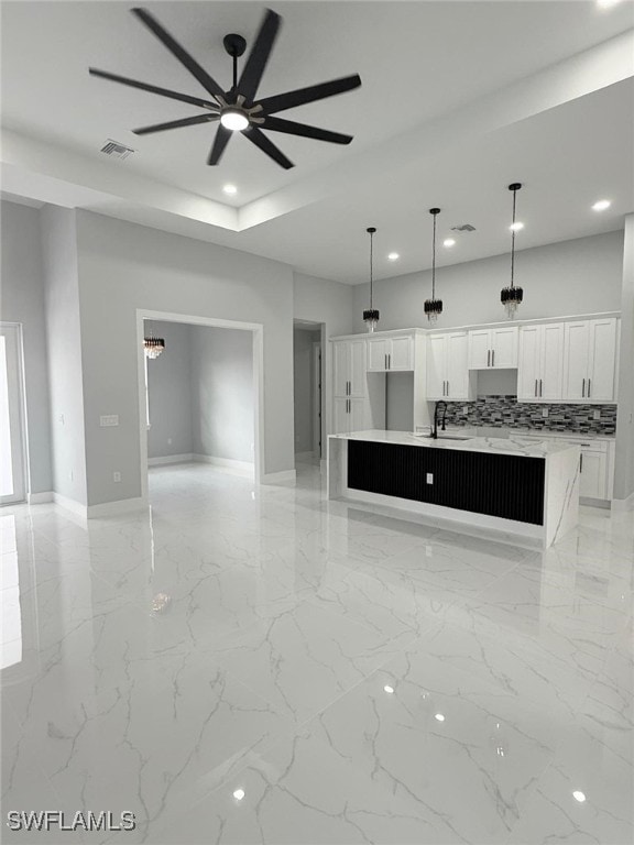 unfurnished living room featuring ceiling fan and sink