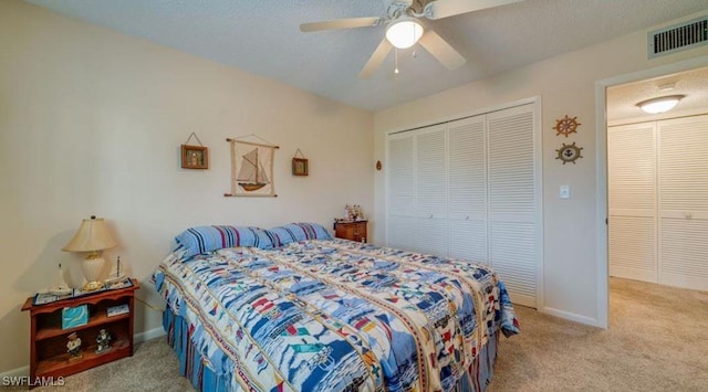 carpeted bedroom with a textured ceiling, ceiling fan, and a closet