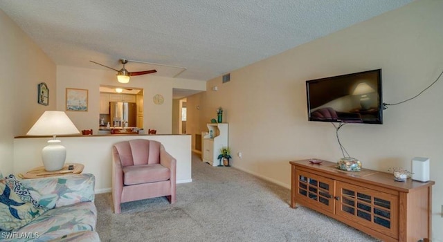 carpeted living room featuring ceiling fan and a textured ceiling