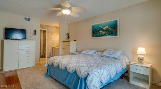 bedroom featuring ceiling fan, light colored carpet, and a textured ceiling