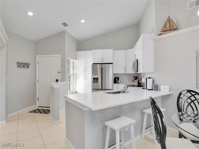 kitchen with appliances with stainless steel finishes, white cabinetry, lofted ceiling, sink, and kitchen peninsula