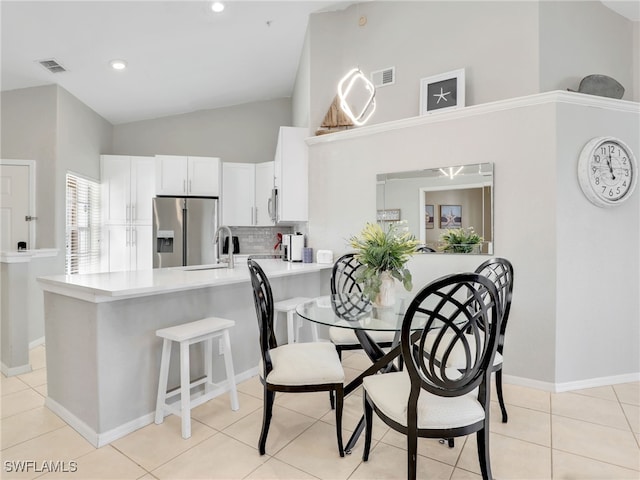 tiled dining space featuring sink and high vaulted ceiling