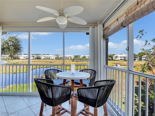 sunroom / solarium with ceiling fan and a water view