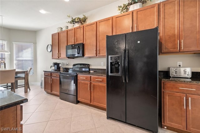 kitchen with light tile patterned floors, dark stone counters, and black appliances