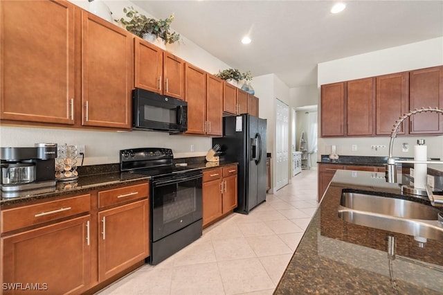 kitchen featuring sink, dark stone countertops, light tile patterned floors, and black appliances