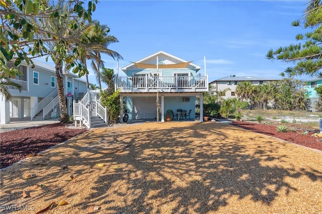 back of property featuring an attached garage, stairway, and a wooden deck