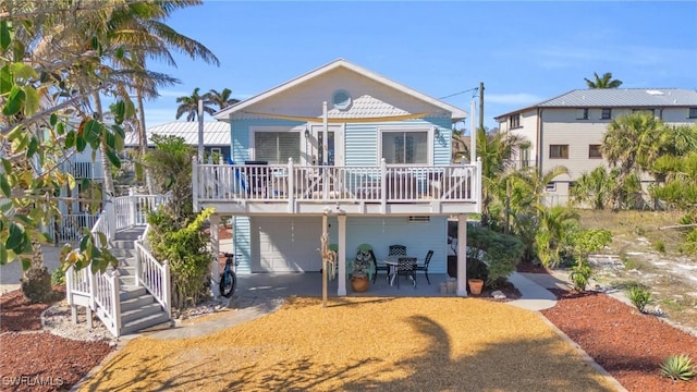 back of property featuring a garage, covered porch, a patio, and stairs