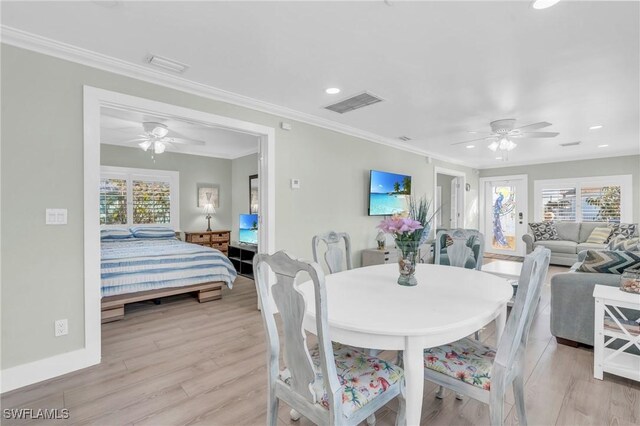 dining room with crown molding, light hardwood / wood-style floors, and a wealth of natural light