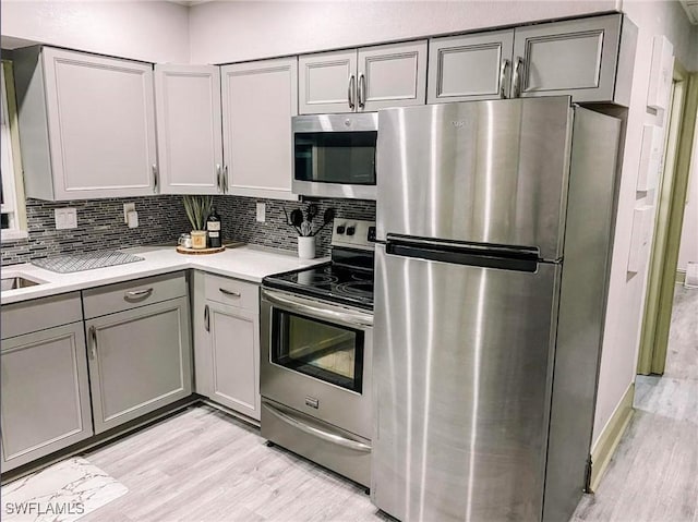 kitchen with tasteful backsplash, appliances with stainless steel finishes, and gray cabinetry