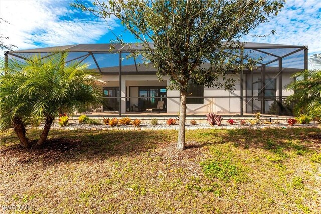 back of house with a lawn, a patio, and glass enclosure