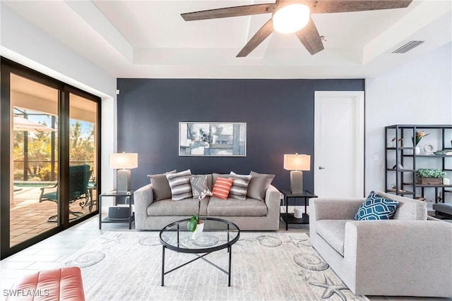 living room with a raised ceiling and ceiling fan