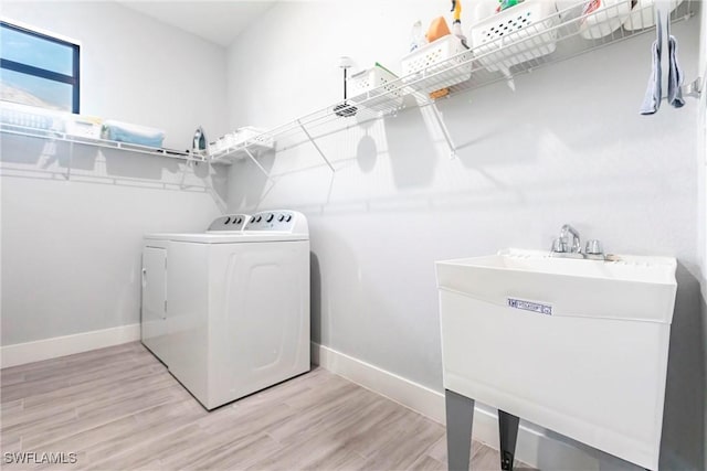 laundry area with washing machine and dryer, sink, and light hardwood / wood-style flooring