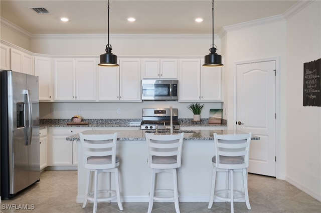 kitchen featuring white cabinetry, hanging light fixtures, stainless steel appliances, and an island with sink