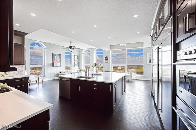 kitchen featuring sink, appliances with stainless steel finishes, dark hardwood / wood-style floors, a kitchen island with sink, and decorative backsplash